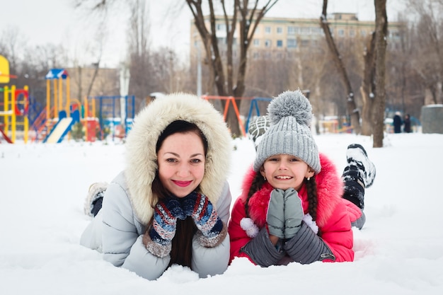 Две счастливые девочки, мать и дочь, играя на детской площадке в городском парке.