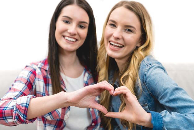 The two happy girls show the heart symbol on the white background