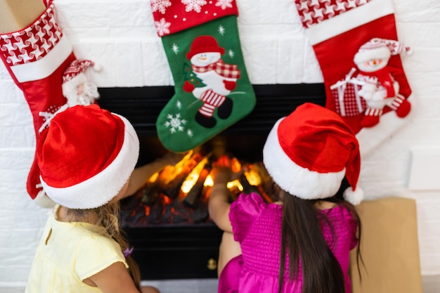 two happy girls sitting at fireplace on Christmas eve