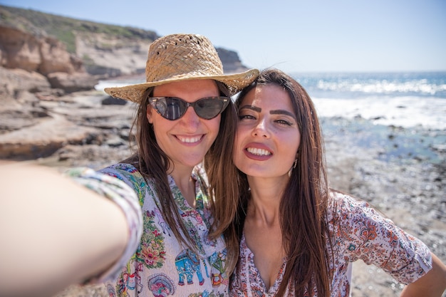 Две счастливые девушки в отпуске делают селфи на пляже