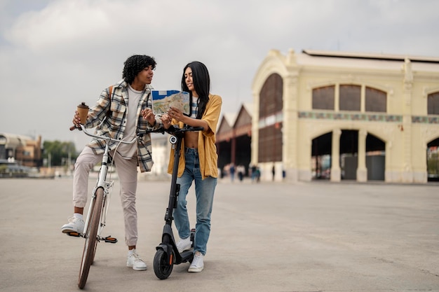 Two happy hipster friends are visiting city sights with their ecofriendly rides