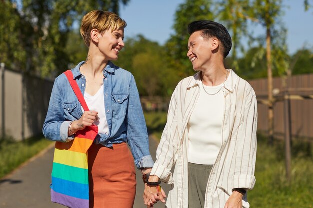 Photo two happy lesbians smiling and talking to each other while walking along the street