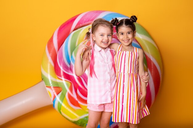 Two happy little girls in colorful dress laughing hugging having fun.