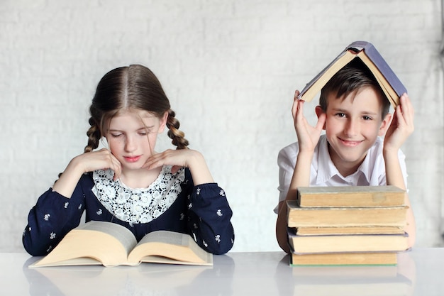 Two of happy little school children boy and girl reading book