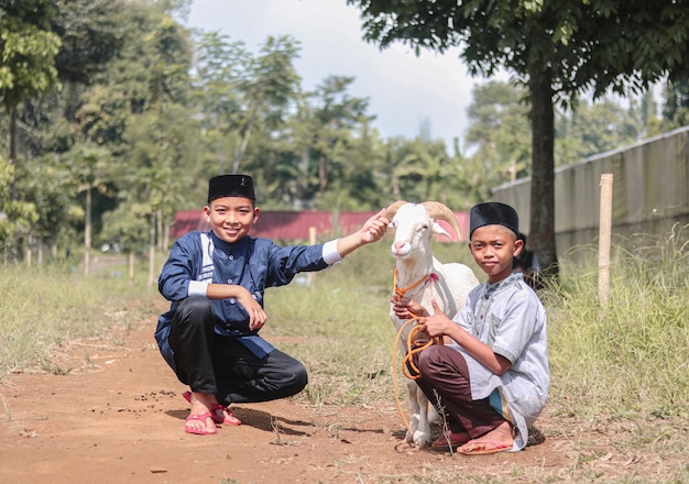 two happy muslim kids playing with goats