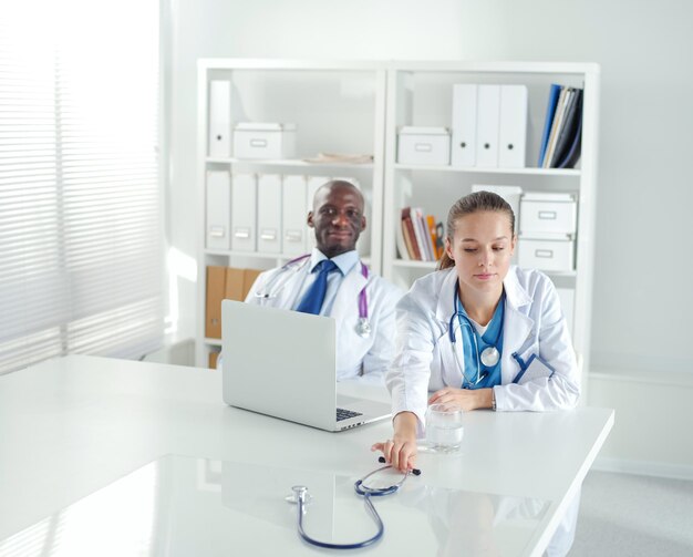 Two happy smiling young medical people handshaking at\
office