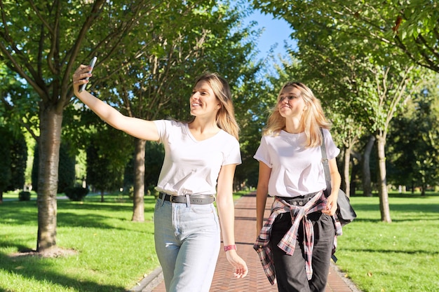 Two happy teenage girls looking at webcam of smartphone girls take selfie photo talk online with friends Youth lifestyle teenagers communication friendship