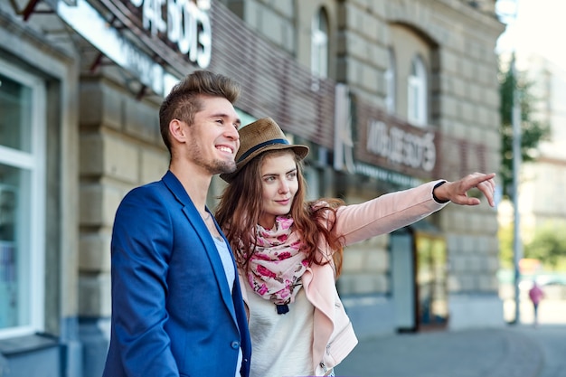 Two happy tourists couple searching location together with a phone and map and pointing with the finger.