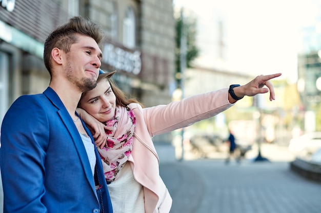 Two happy tourists couple searching location together with a\
phone and map and pointing with the finger.