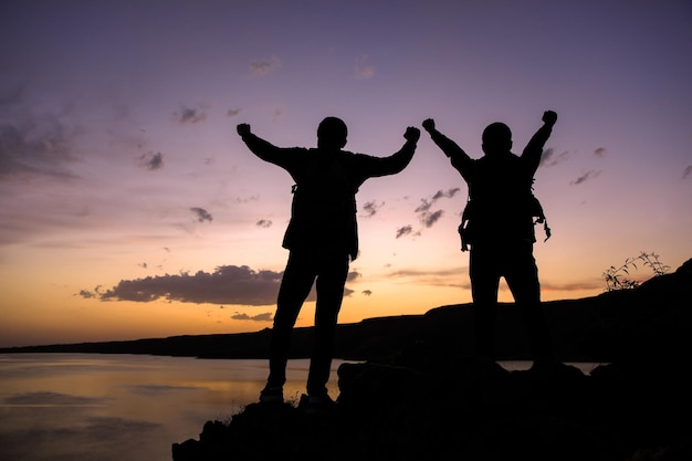 two happy traveler man with lake at the sunset
