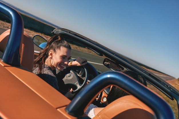 카브리올레에서 운전하고 재미있는 후면보기를 즐기는 두 명의 행복한 여성