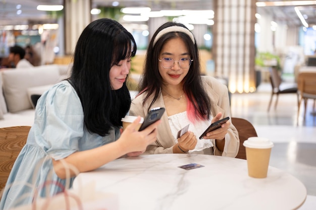 Two happy young Asian female friends are hanging out together at the shopping mall on the weekend