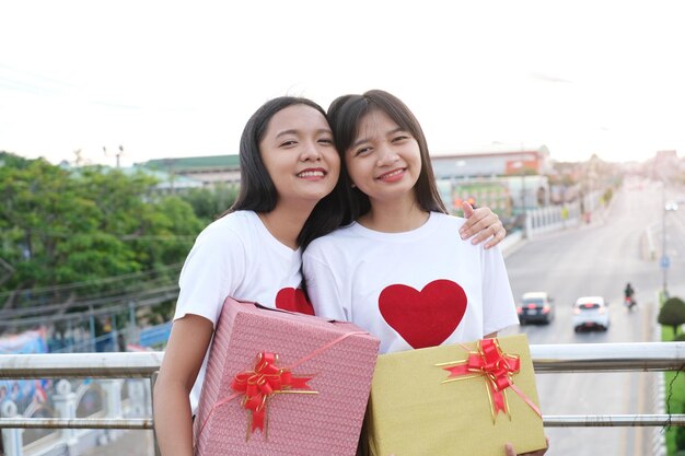 Two happy young girl with gift box on city background