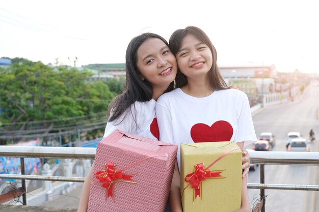 Two happy young girl with gift box on city background