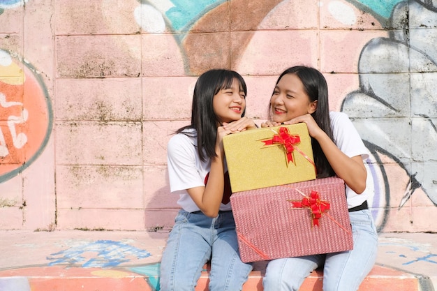 Two happy young girl with gift box on colorful background