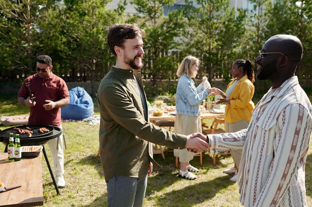 Two happy young intercultural men greeting each other by handshake