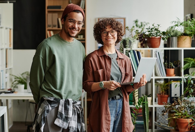 Two happy young programmers in casualwear looking at you