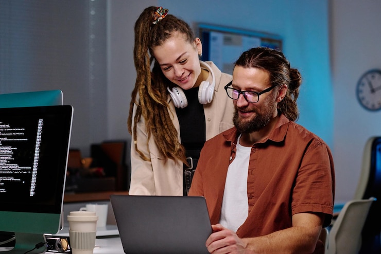 Photo two happy young programmers looking at laptop screen with coded data