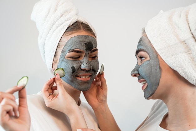 Photo two happy young woman apply clay mask on face enjoy free time