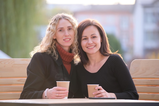 Two happy young women sitting at city street cafe havinh fun
time together during coffee break.