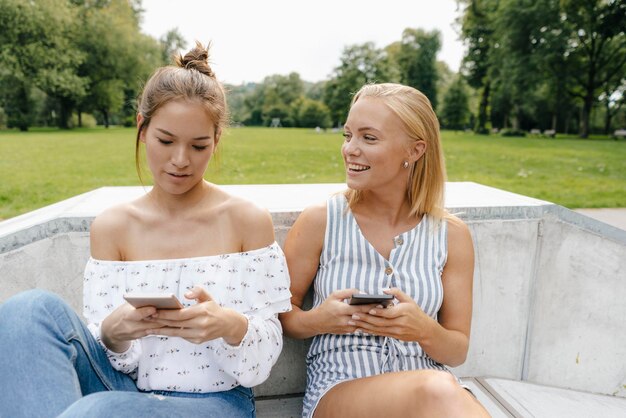 Two happy young women with cell phones in a skatepark