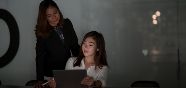 Two hard-working businesswomen discussing the project together at night time