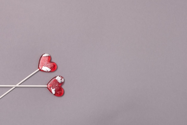 회색 종이 배경 사랑 개념 평면도 미니멀리즘 스타일에 두 개의 심장 모양 롤리팝 사탕