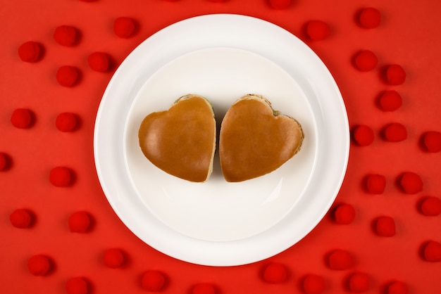 Two heart-shaped burgers on a white plate