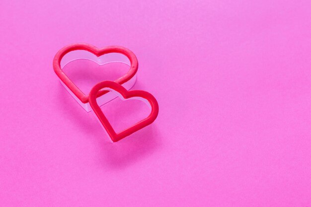 Two heart-shaped forms set on hot pink background with copy space