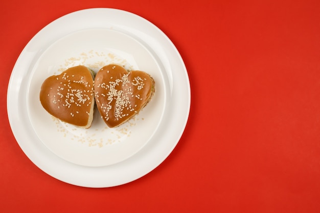 Two heart-shaped sesame burgers on a white plate