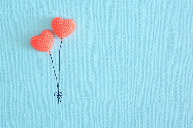 two hearts of coral color on blue paper in the form of balloons. copy space.