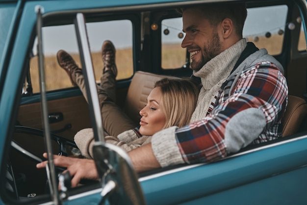 Due cuori pieni d'amore. attraente giovane donna che riposa tra le braccia del suo ragazzo mentre viaggia in mini furgone in stile retrò