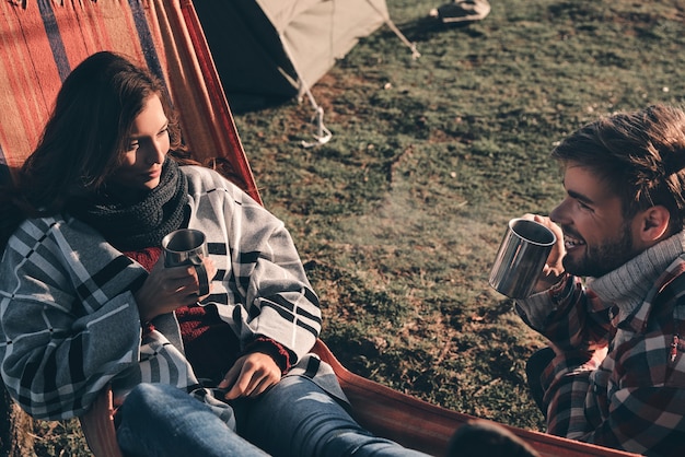 Foto due cuori pieni d'amore. vista dall'alto di una bella giovane coppia che beve il caffè mattutino mentre si accampa in montagna
