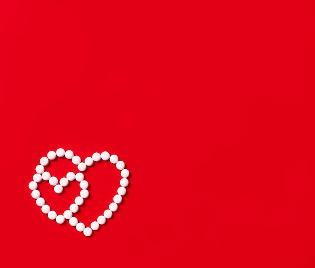 Two hearts made of round white pills on a red background