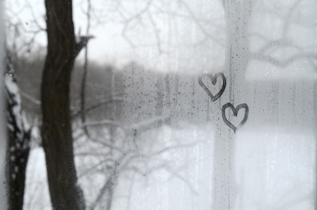 Два сердца нарисованы на запотевшем стекле зимой