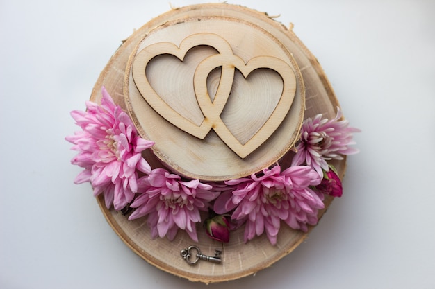 Foto due cuori su una fetta di legno e fiori rosa