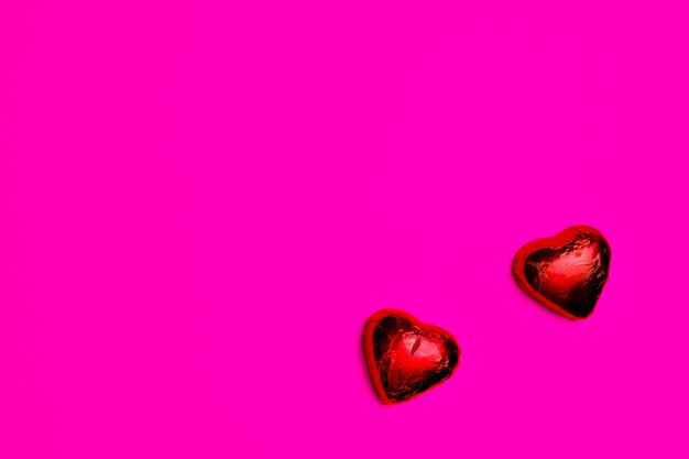 two heartshaped chocolates with pink background copy space2