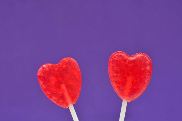 Two heartshaped lollipops on a lilac background