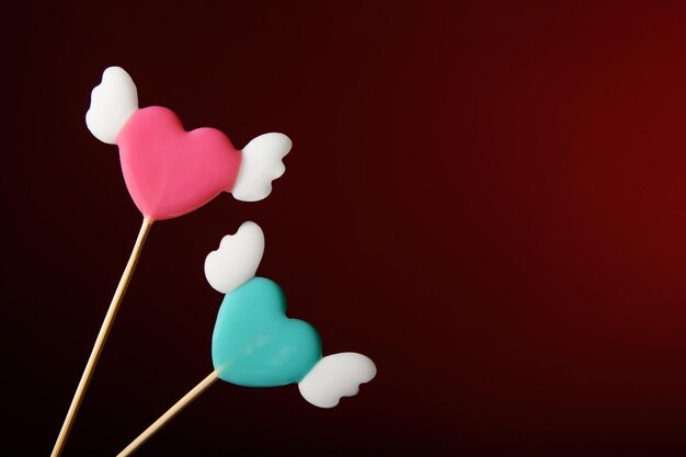 Two heartshaped lollipops with wings on a dark red background Love banner for Valentines Day