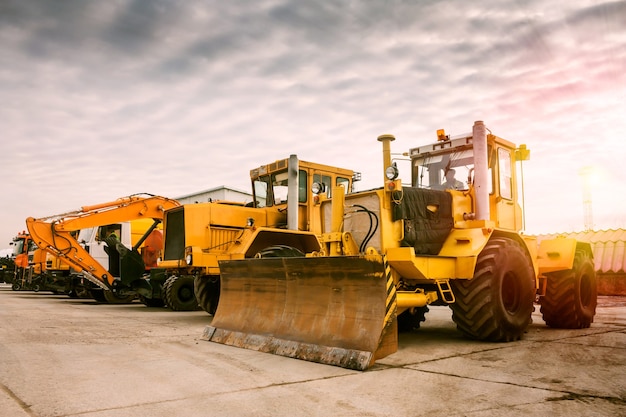 Two heavy wheeled tractor one excavator and other construction machinery in the morning sun