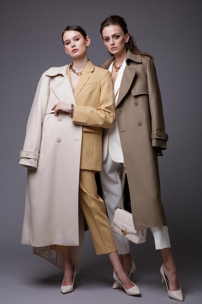 Две модели высокой моды в бежевом белом пальто, пиджаке, брюках, брюках, аксессуарах, сумочках