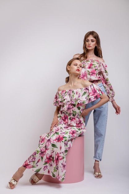 Two high fashion models in long dress with a red floral pattern blouse blue jeans Beautiful women