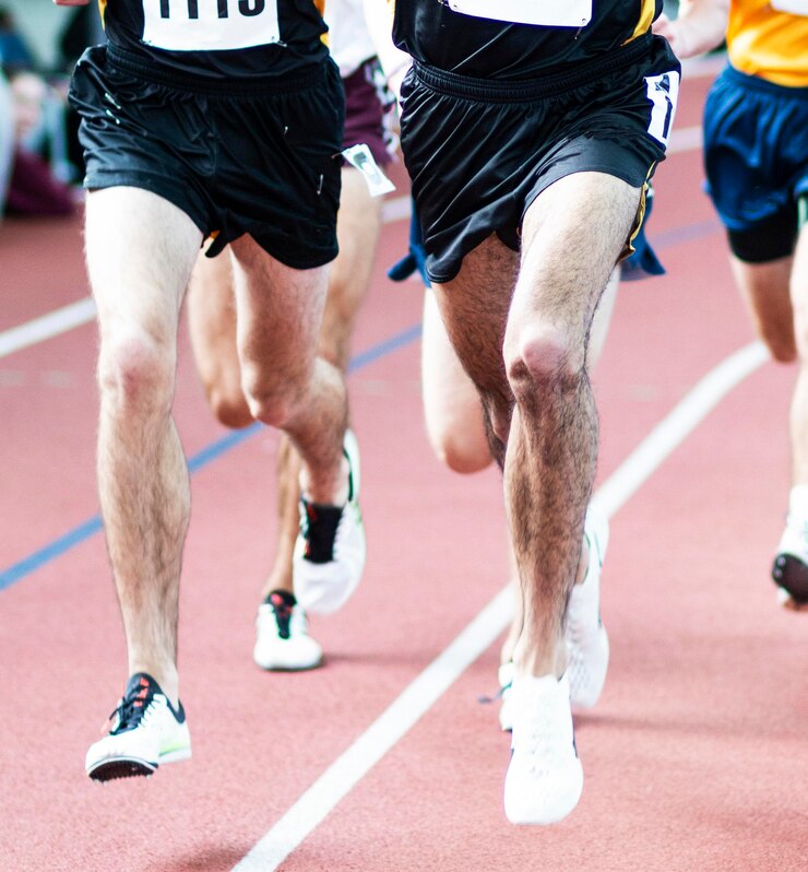 Photo two high school boys from the same team are leading the mile on an indoor track during a race