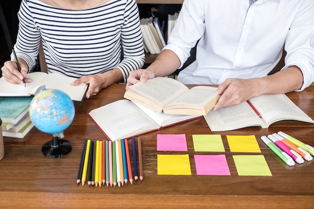 Foto gruppo di studenti di due liceo seduto in biblioteca con l'aiuto amico facendo i compiti e la pratica della lezione