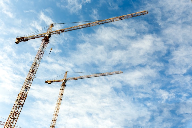 Two high tower cranes work on a construction of new homes