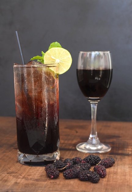 Two highball mulberry wine cocktail with glass of wine on wooden table and black background