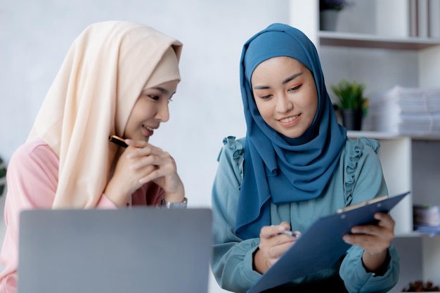 Due donne asiatiche vestite di hijab stanno facendo brainstorming insieme in una sala conferenze per una startup gestita da una giovane donna di talento il concetto di gestione gestisce l'azienda di leader femminili per far crescere l'azienda