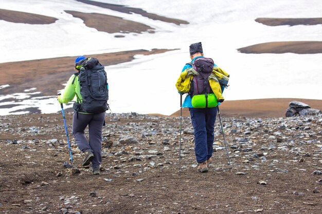 두 명의 등산객이 아이슬란드 산의 하이킹 코스를 따라 걷고 있습니다. Landmannalaugar