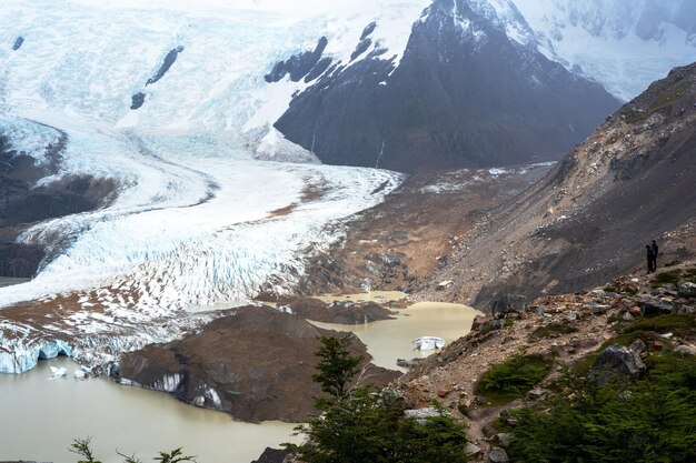 two hikers staring to a glacier melting and forming lake in Glacier Park in Argentina