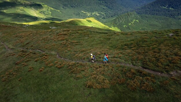 Two hikers with backpacks are walking along mountain range in Carpathian mountains